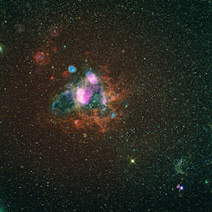 A colorful nebula glowing with shades of pink and purple, framed by distant stars.