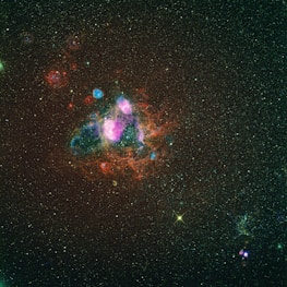 A close-up of a vibrant nebula glowing in shades of purple and pink against the dark space.
