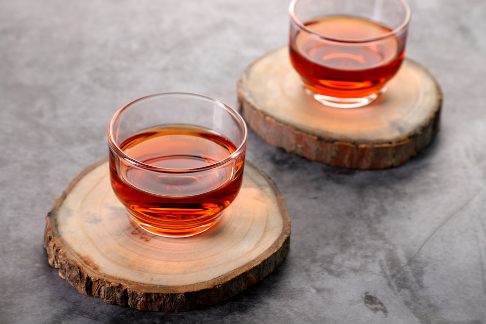 tasse en verre transparent avec un liquide rouge sur une table en bois brun