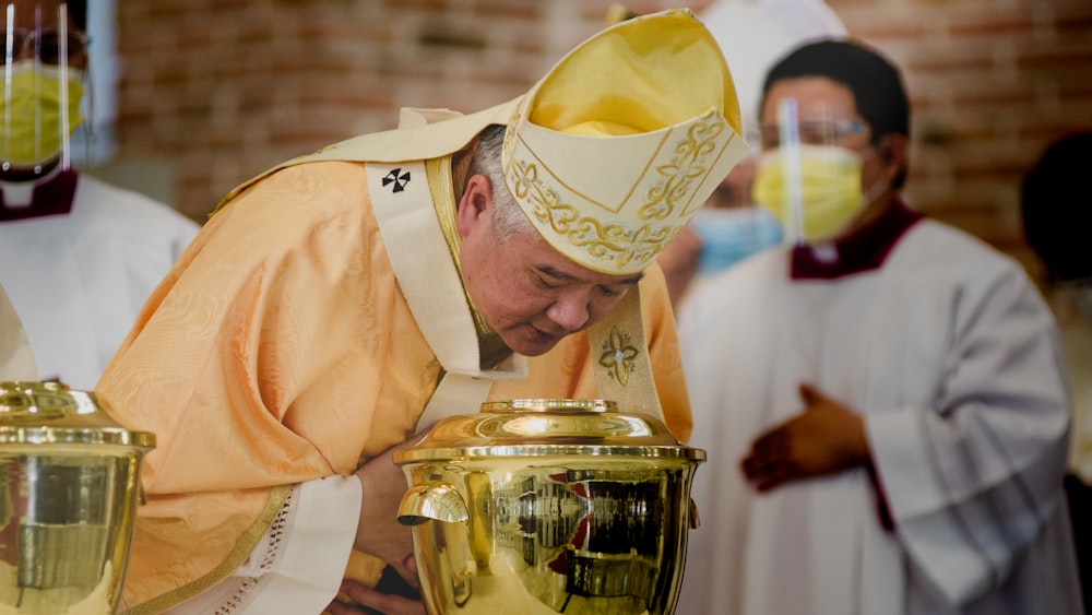 man in yellow thobe holding gold container