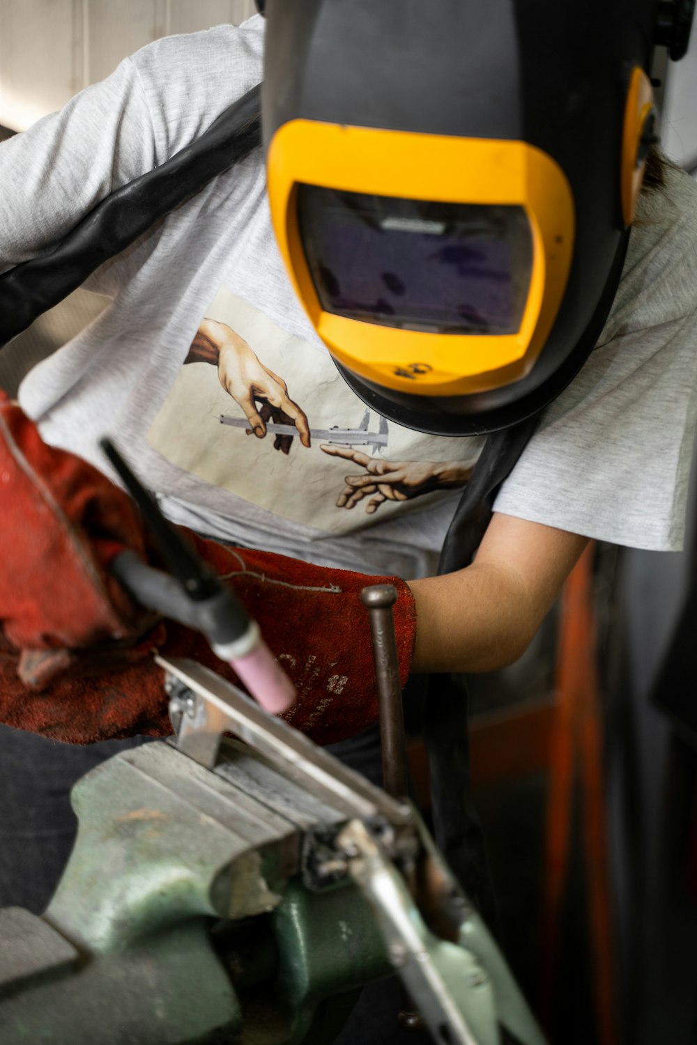 person in white t-shirt holding brown and gray metal tool