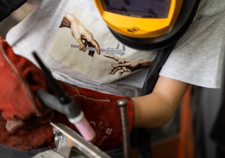 person in white t-shirt holding brown and gray metal tool