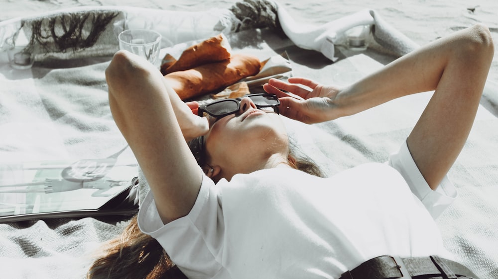 woman in white shirt lying on white textile