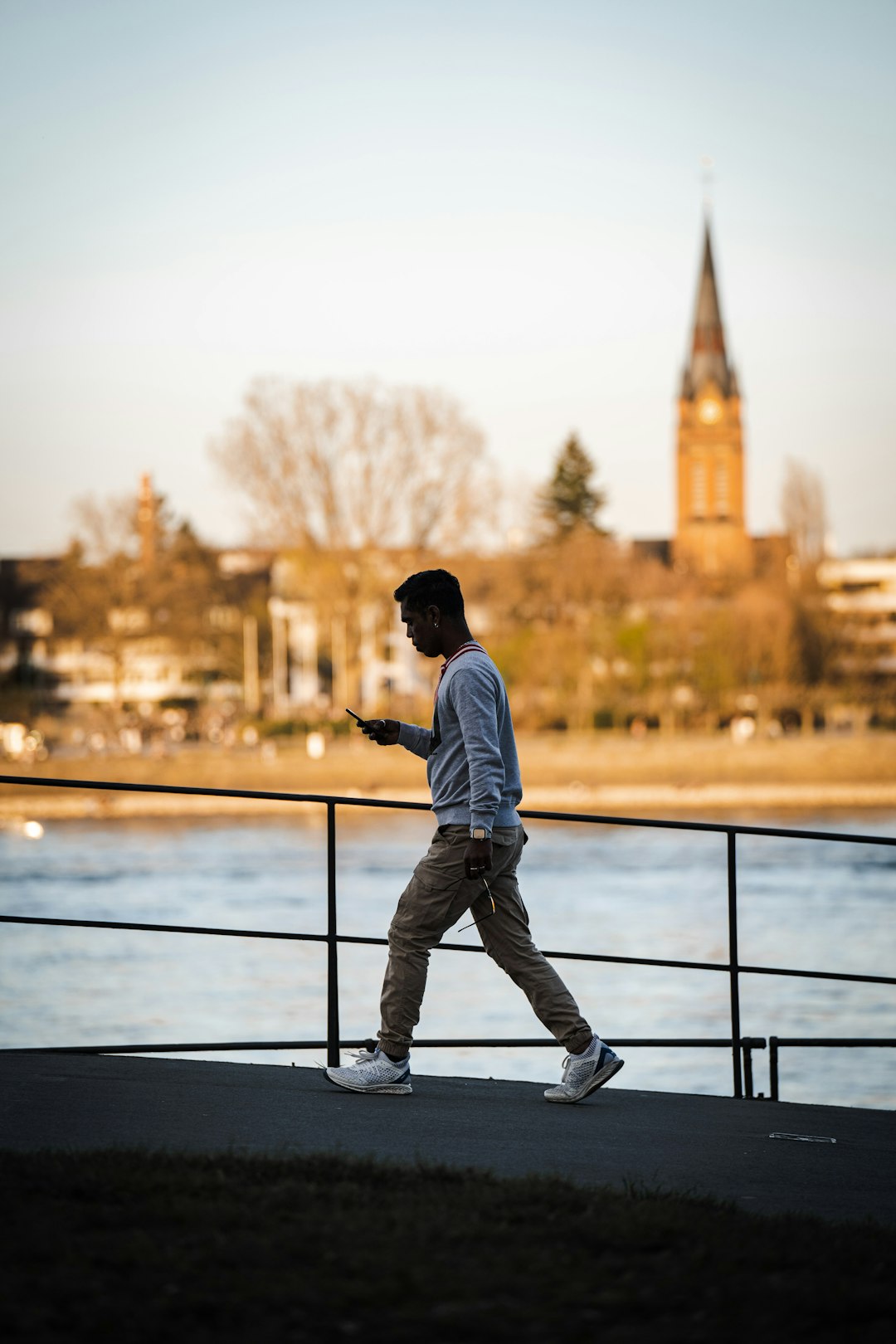 man in white dress shirt and black pants standing on black metal railings during daytime