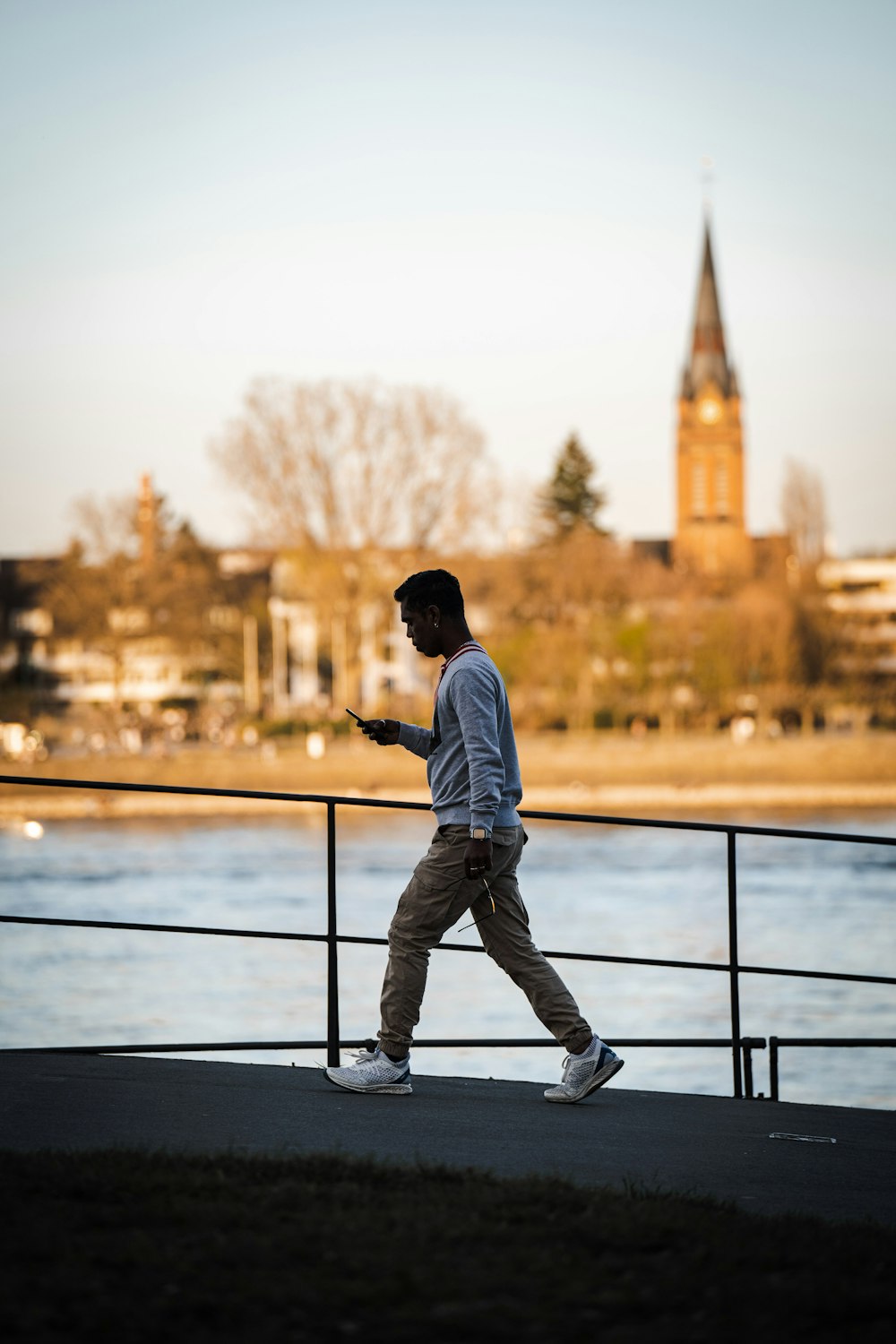 man in white dress shirt and black pants standing on black metal railings during daytime