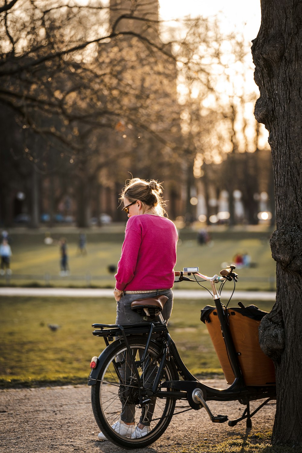 紫色の長袖シャツを着た女性が昼間、道路を自転車で走っている