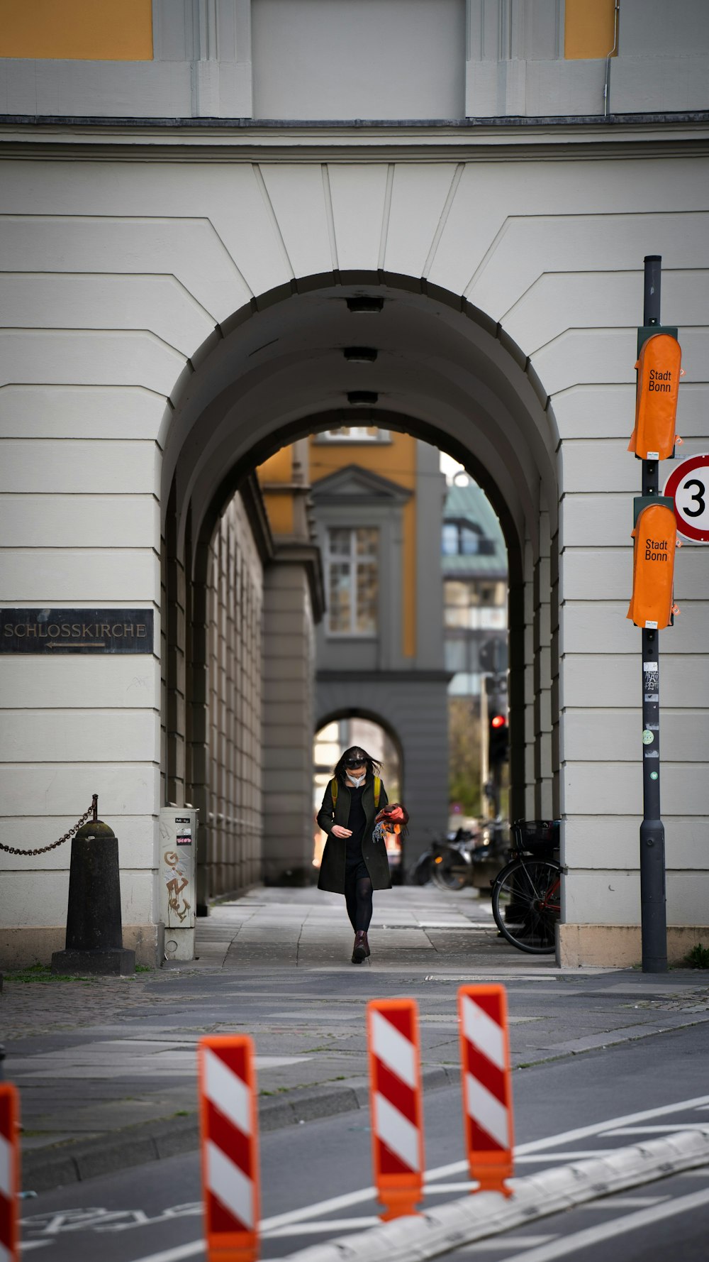 woman in black jacket walking on sidewalk during daytime