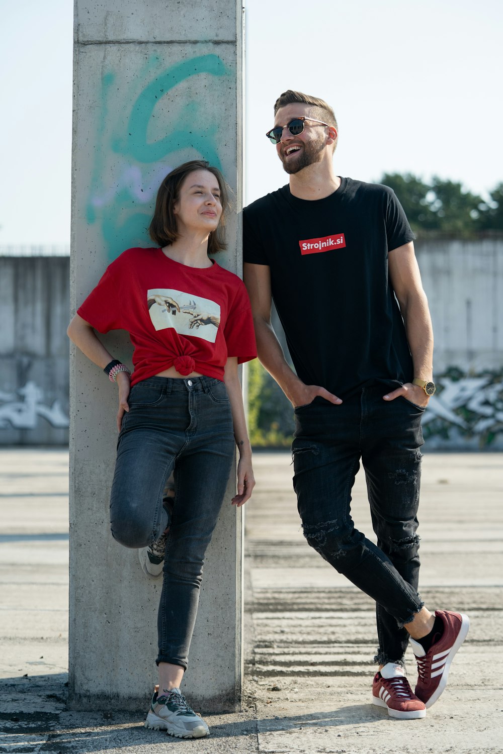 Mann im schwarzen Rundhals-T-Shirt steht neben der Frau im roten Rundhals-T-Shirt