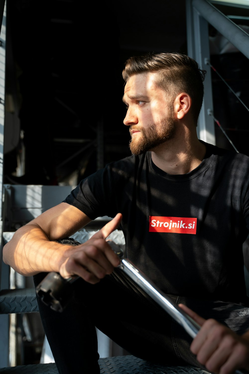 man in black crew neck t-shirt holding black metal pipe