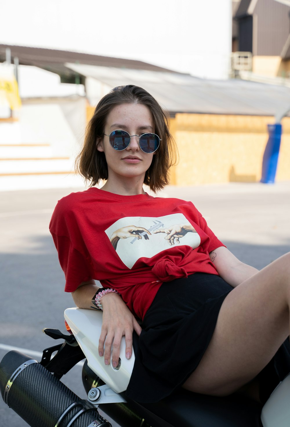 woman in red and white crew neck t-shirt and black skirt sitting on white bench