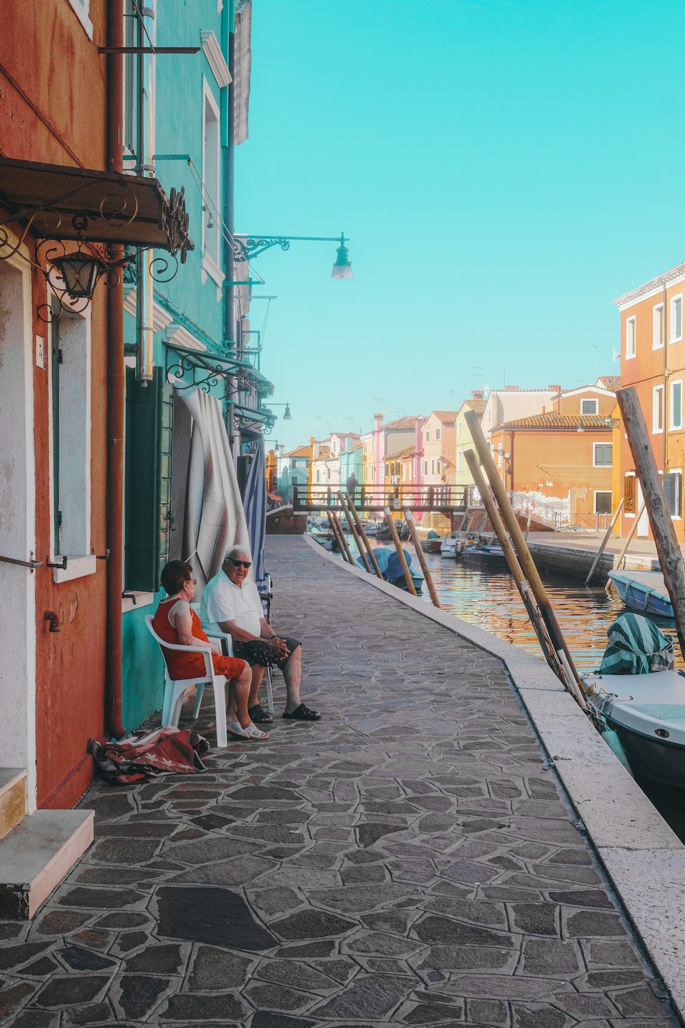 man in blue shirt sitting on chair near blue boat during daytime