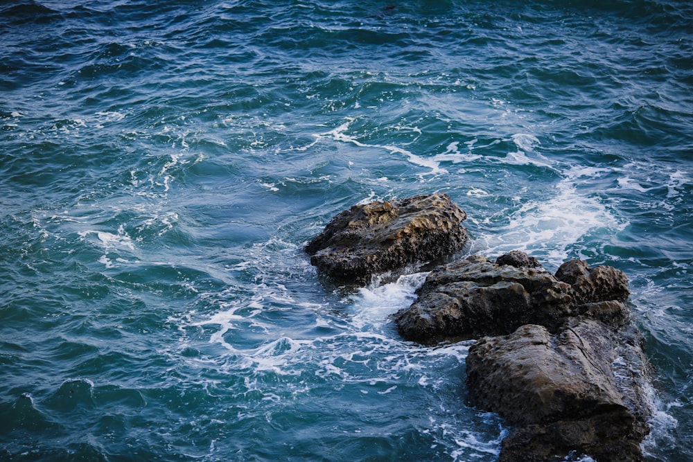 formação rochosa marrom no mar durante o dia