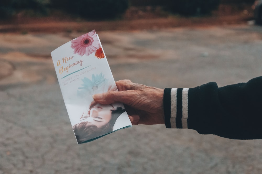 personne tenant une carte florale blanche et rose