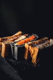 A collection of gourmet sandwiches is arranged artistically on a dark slate surface. The toasted sandwich slices display varied fillings, including a notable slice with vibrant orange roe, contrasting against the darker shades of the bread.