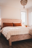 Cozy bedroom featuring crisp white linens and a light salmon orange throw pillow.