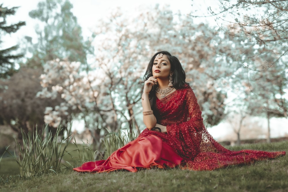 woman in red dress sitting on grass field