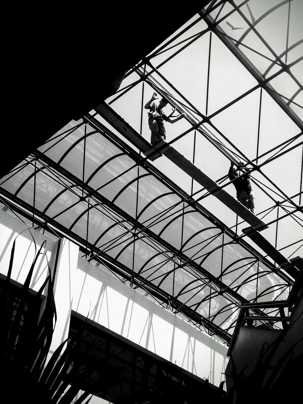 grayscale photo of man in black suit standing on glass roof