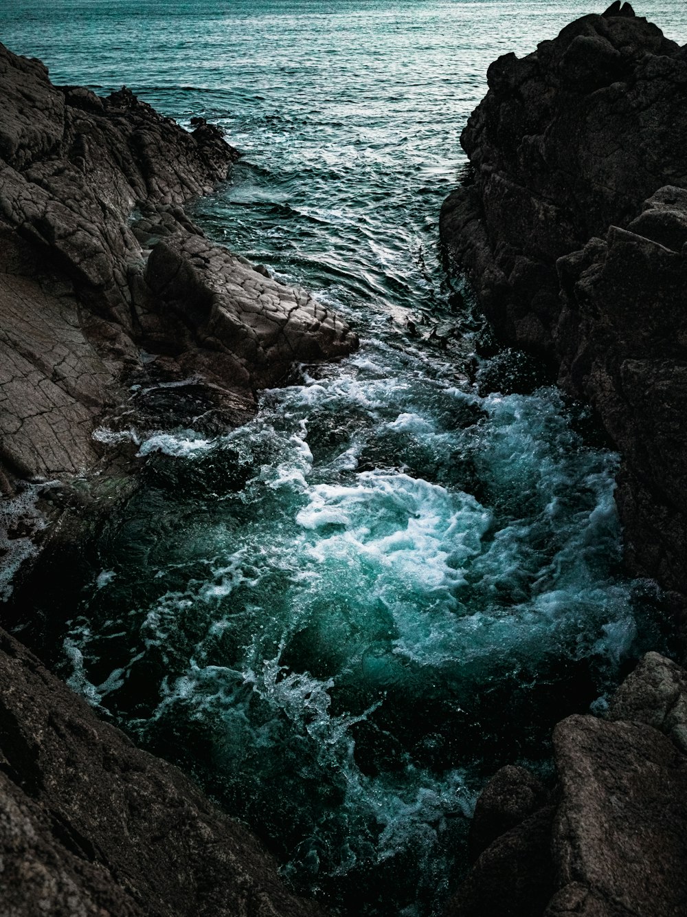 brown rocky mountain beside body of water during daytime