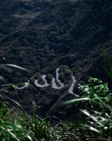 A scenic view of a winding road through lush green mountains, inviting adventure