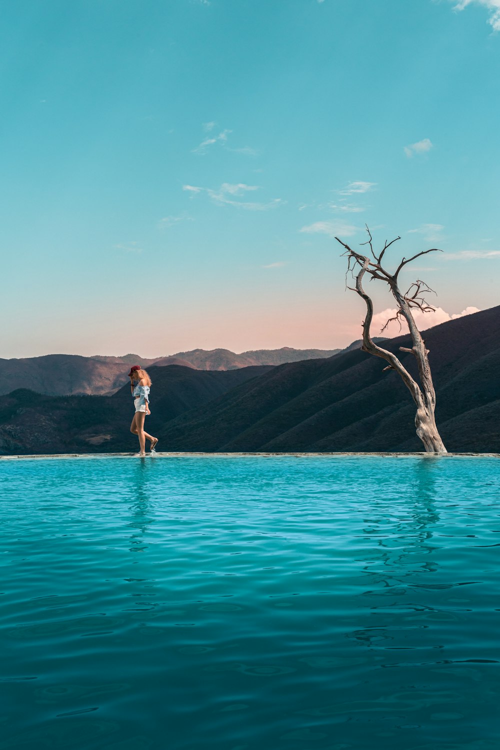 Mujer en vestido blanco de pie sobre agua azul durante el día