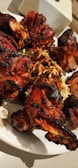 Freshly prepared tandoori chicken with charred edges and a sprinkle of herbs.