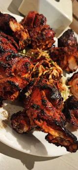 Grilled chicken pieces sizzling on a rustic wooden platter with herbs.