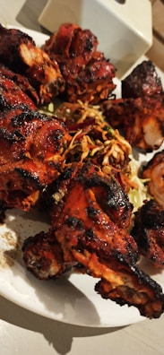 Freshly prepared tandoori chicken with charred edges and a sprinkle of herbs.