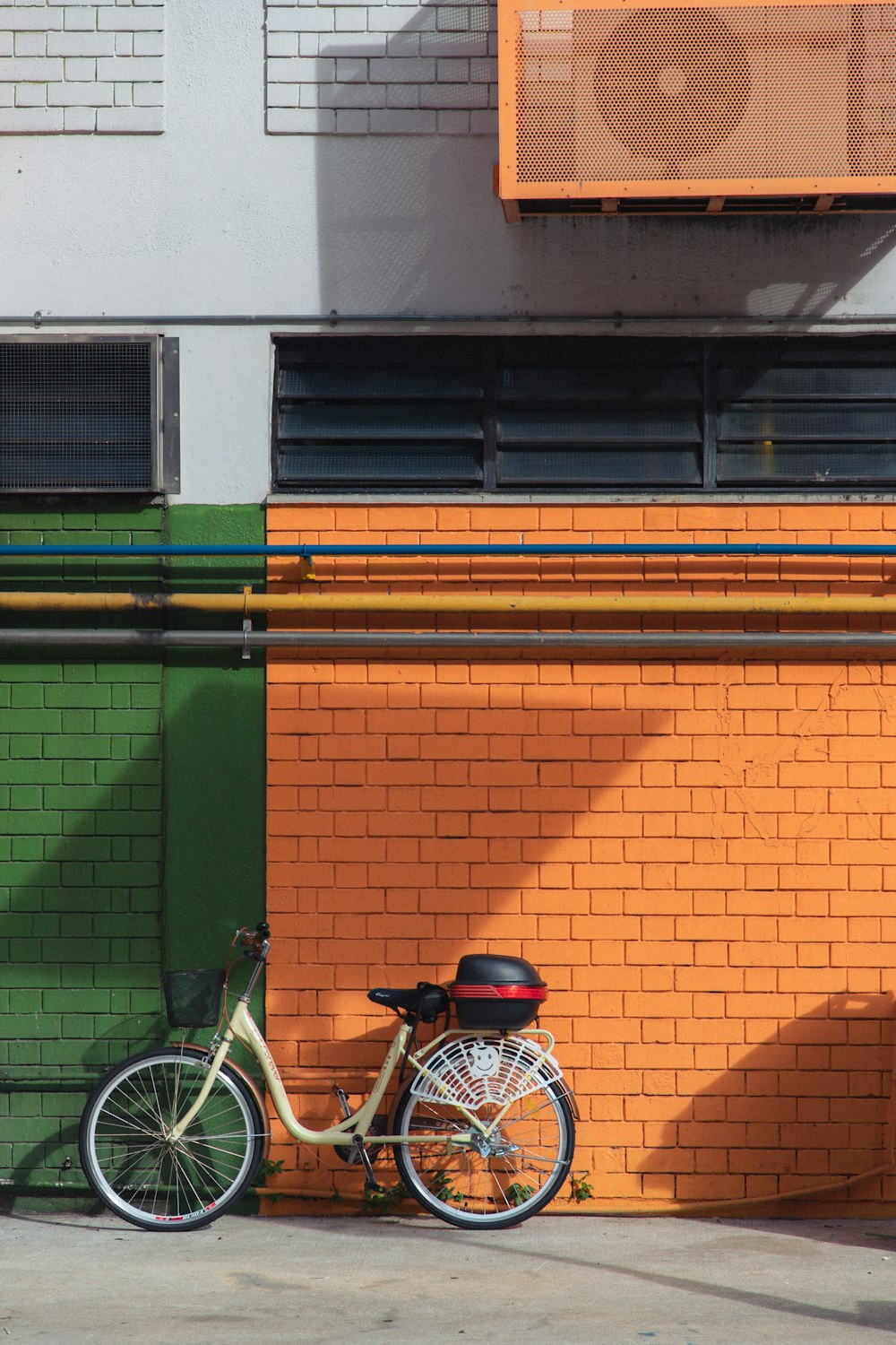 녹색과 갈색 콘크리트 건물 옆에 주차된 파란색과 흰색 통근 자전거