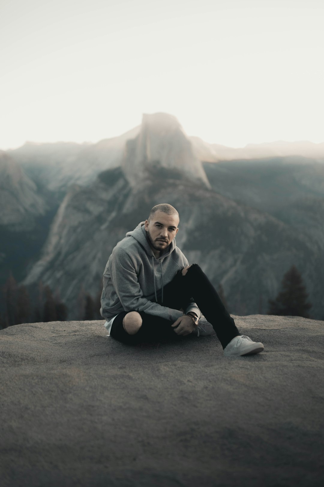 man in gray hoodie sitting on gray rock