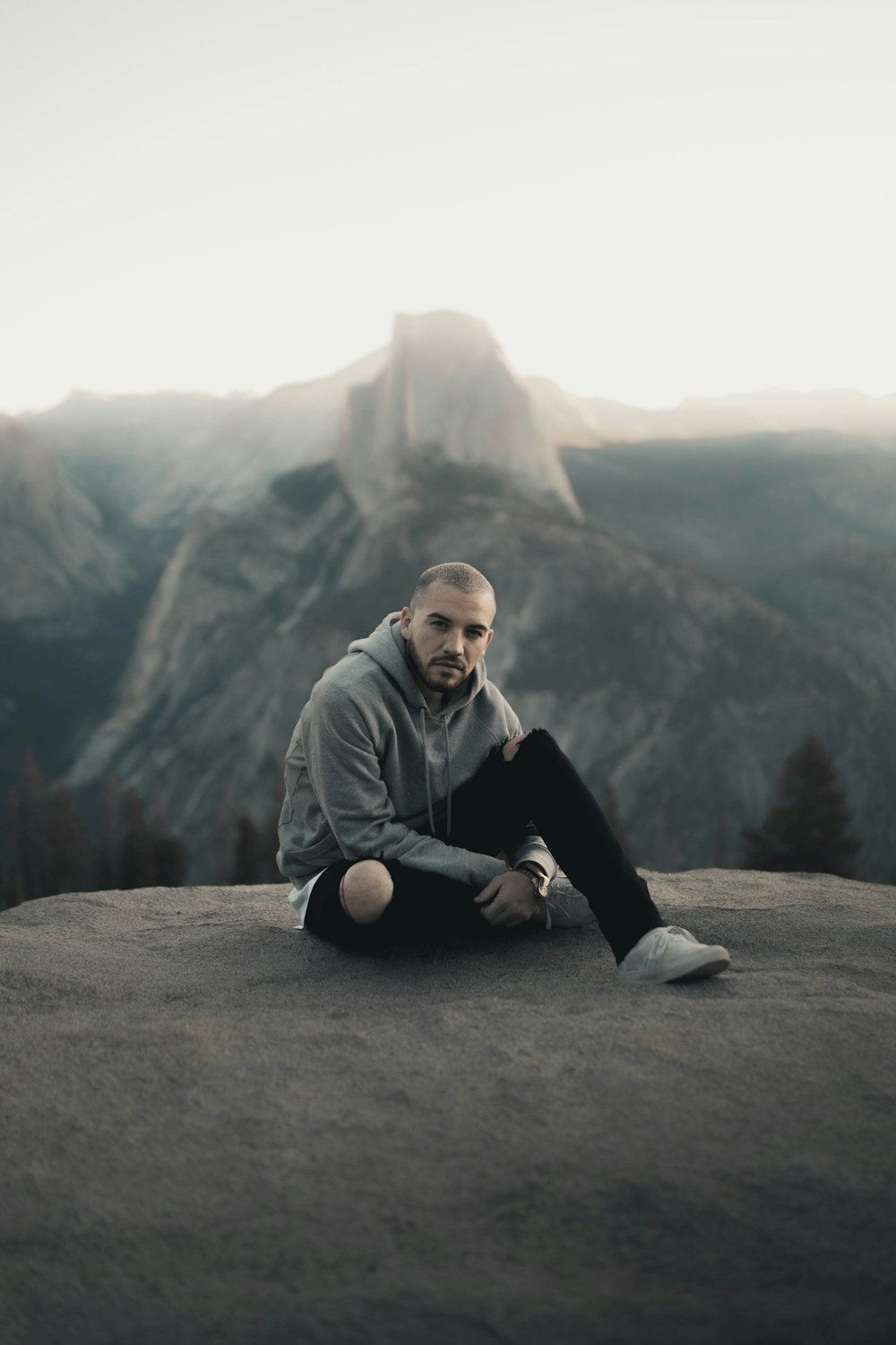 man in gray hoodie sitting on gray rock