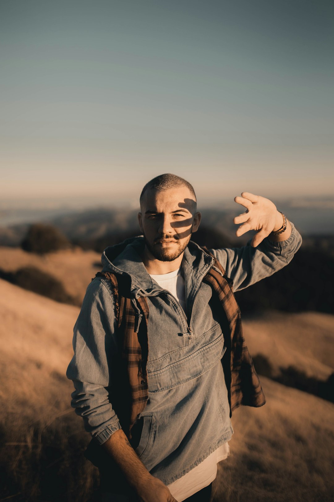 man in black leather jacket standing on brown field during daytime