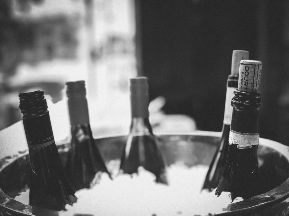 grayscale photography of wine bottle on table