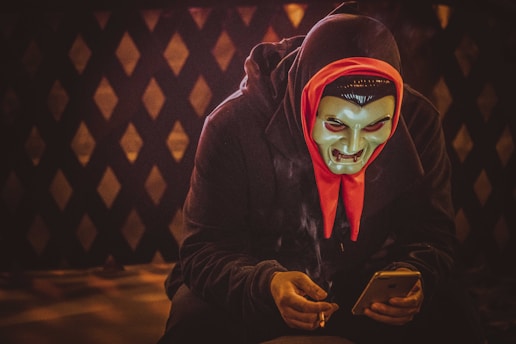 person in black and red mask holding smartphone