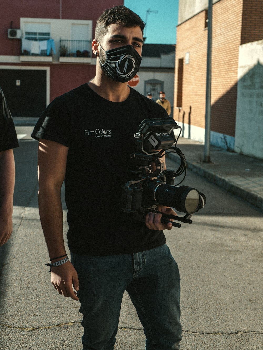 man in black crew neck t-shirt and blue denim jeans holding black dslr camera