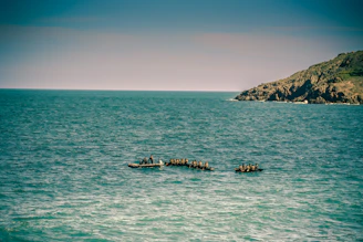 A group paddling canoes across the calm waters of Lake Superior under a cloudy sky.