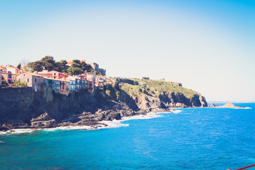 brown and white concrete building on cliff by the sea during daytime