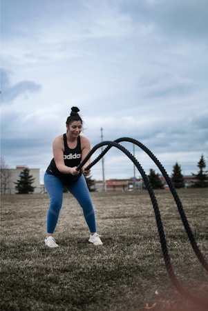 woman in black sports bra and blue denim jeans standing on green grass field during daytime