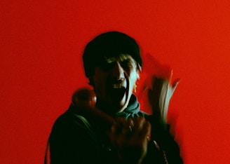 A person is holding a phone receiver against a vibrant red background, appearing animated with blurred motion.