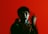 A person is holding a phone receiver against a vibrant red background, appearing animated with blurred motion.