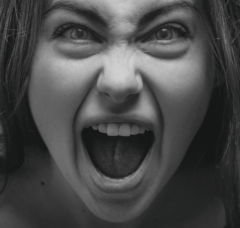 Foto in scala di grigi di donna che mostra la sua lingua