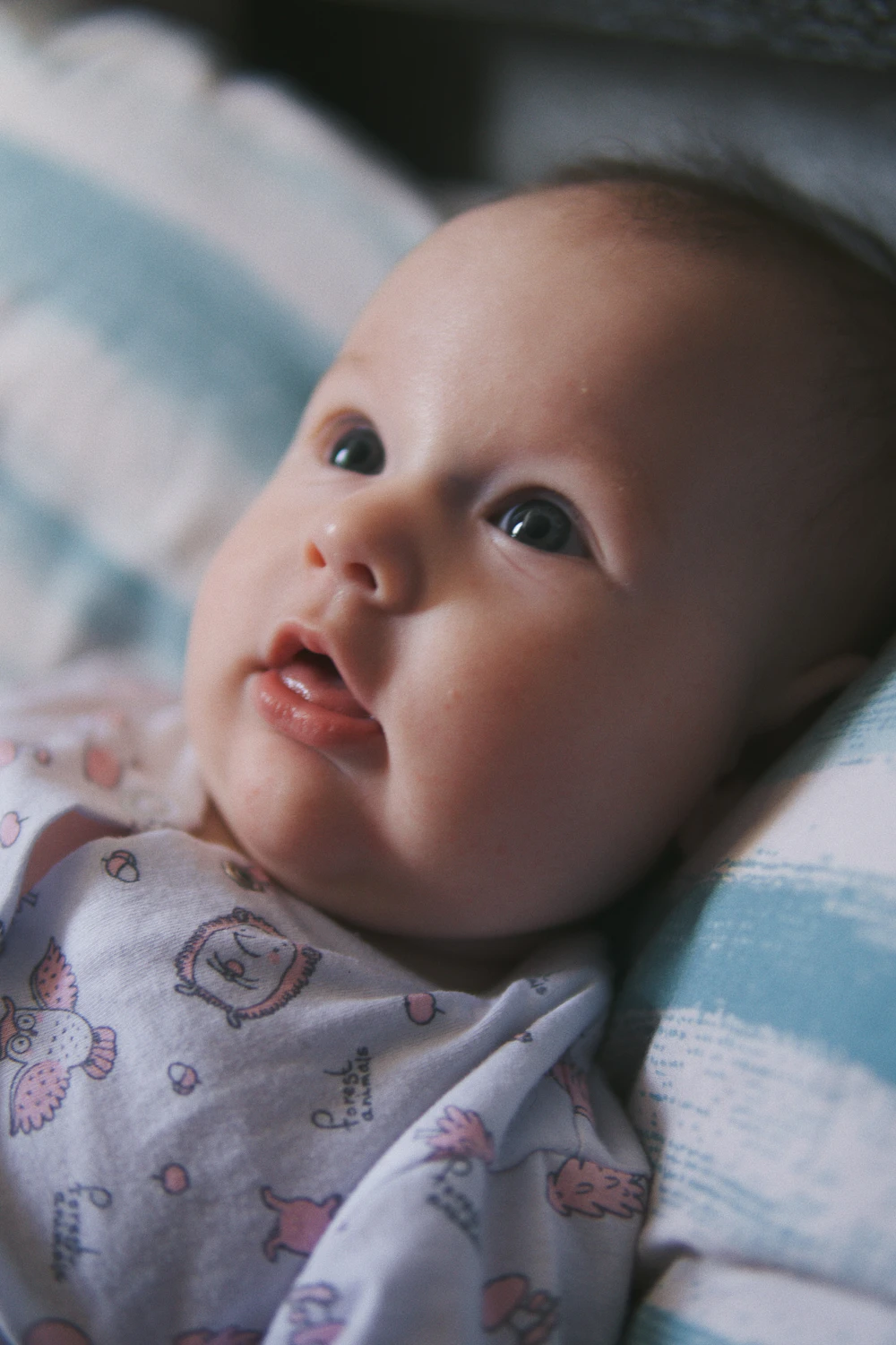 Baby lying comfortably in soft white and blue clothing, warm natural light