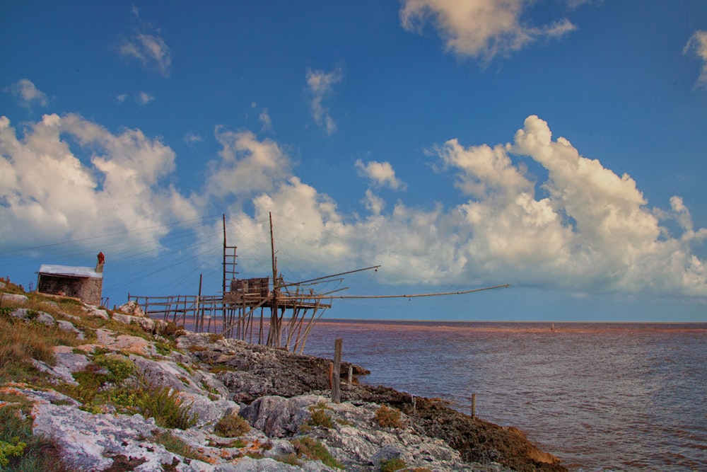 brown wooden dock on sea under blue sky and white clouds during daytime