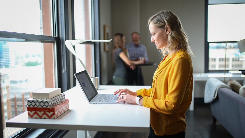 woman in yellow long sleeve shirt using macbook pro