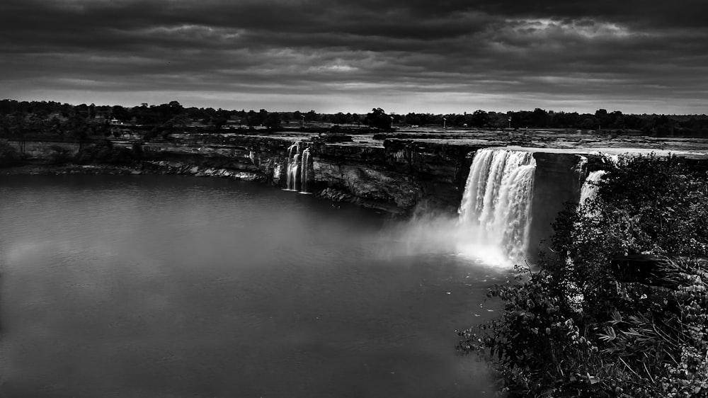 Photo en niveaux de gris de chutes d’eau sous un ciel nuageux