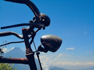 Close-up of a vintage bike handlebar wrapped in worn leather tape, resting against a rustic wooden fence.