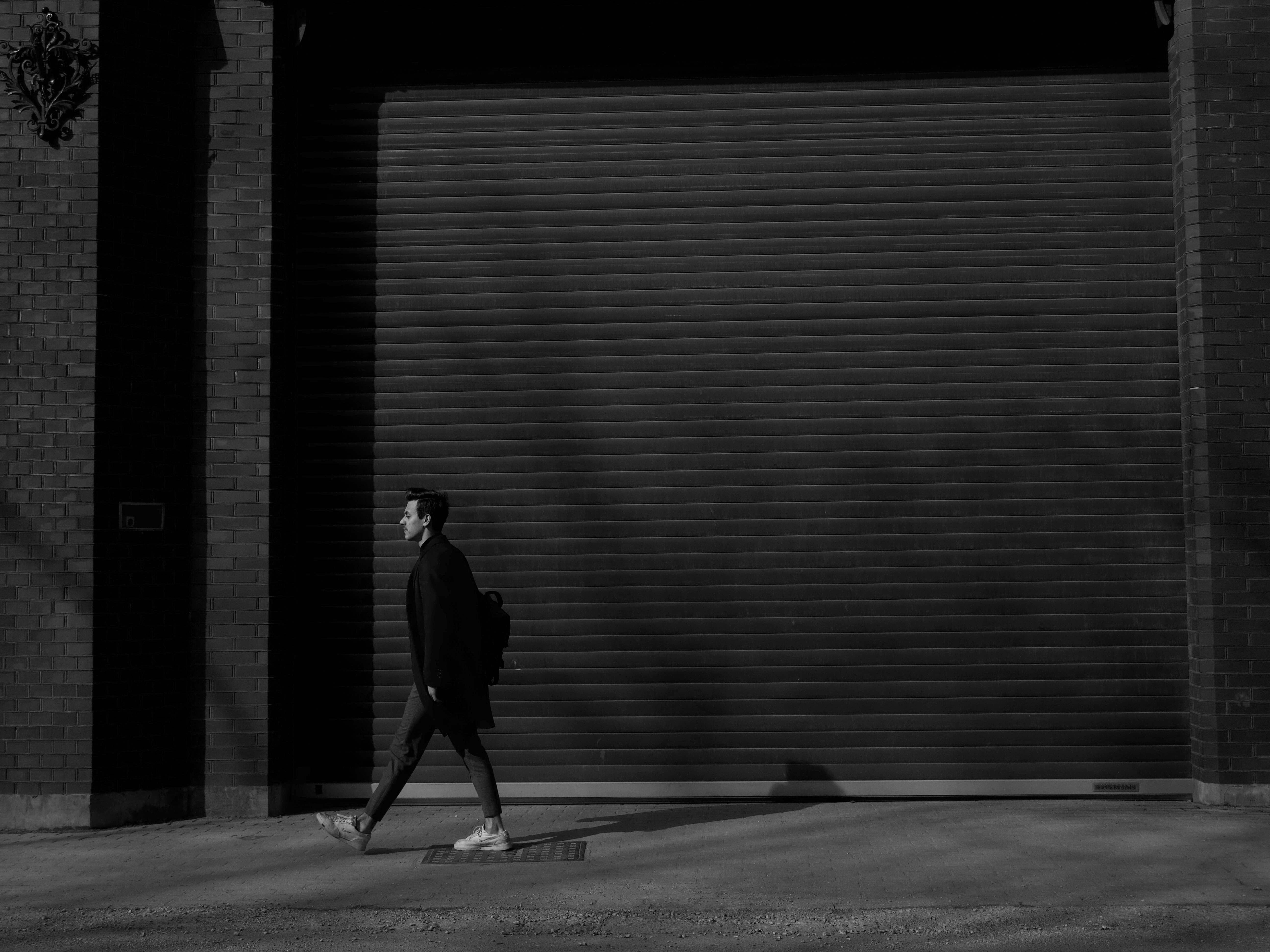 man in black jacket walking on sidewalk during daytime