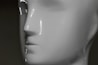 A close-up view of a white mannequin head with a smooth, glossy surface. The image captures the profile of the mannequin, focusing on its nose, lips, and part of the chin. Reflective highlights are present due to the lighting.
