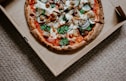 pizza with green leaves on brown box