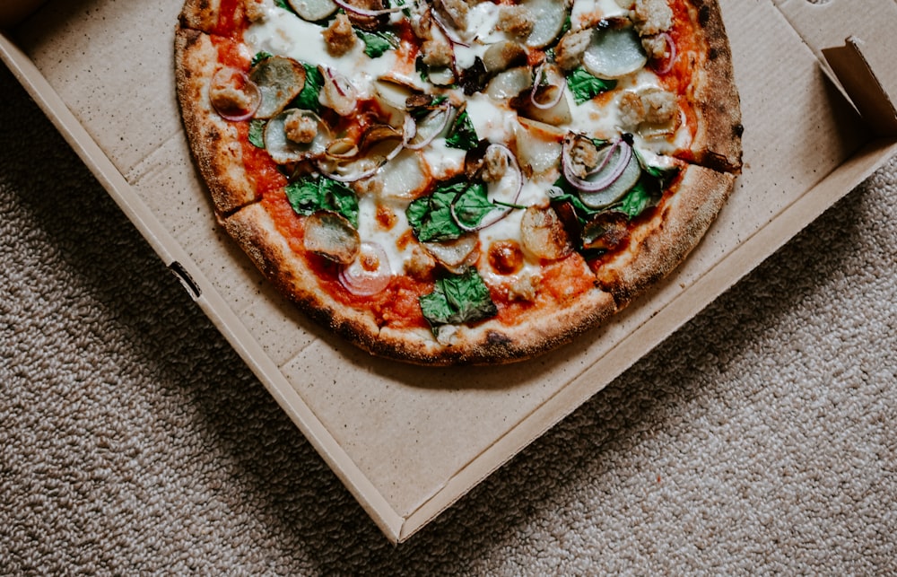 pizza avec des feuilles vertes sur une boîte brune