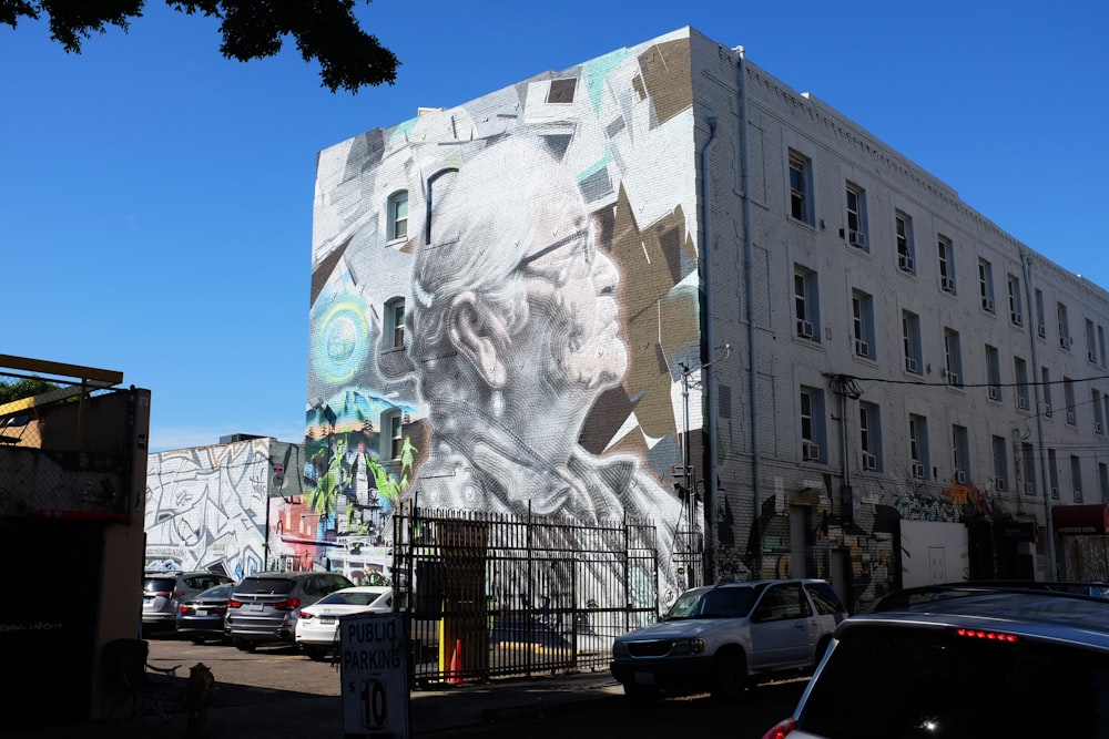 Bâtiment en béton blanc avec l’art mural visage humain pendant la journée